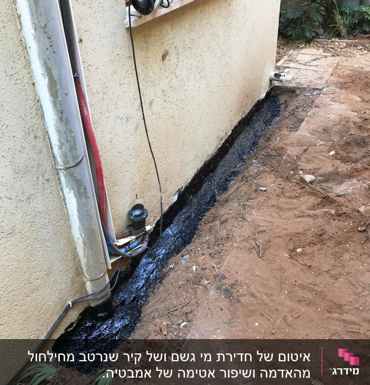 איטום קיר חיצוני עם חומר שחור ליד צינור